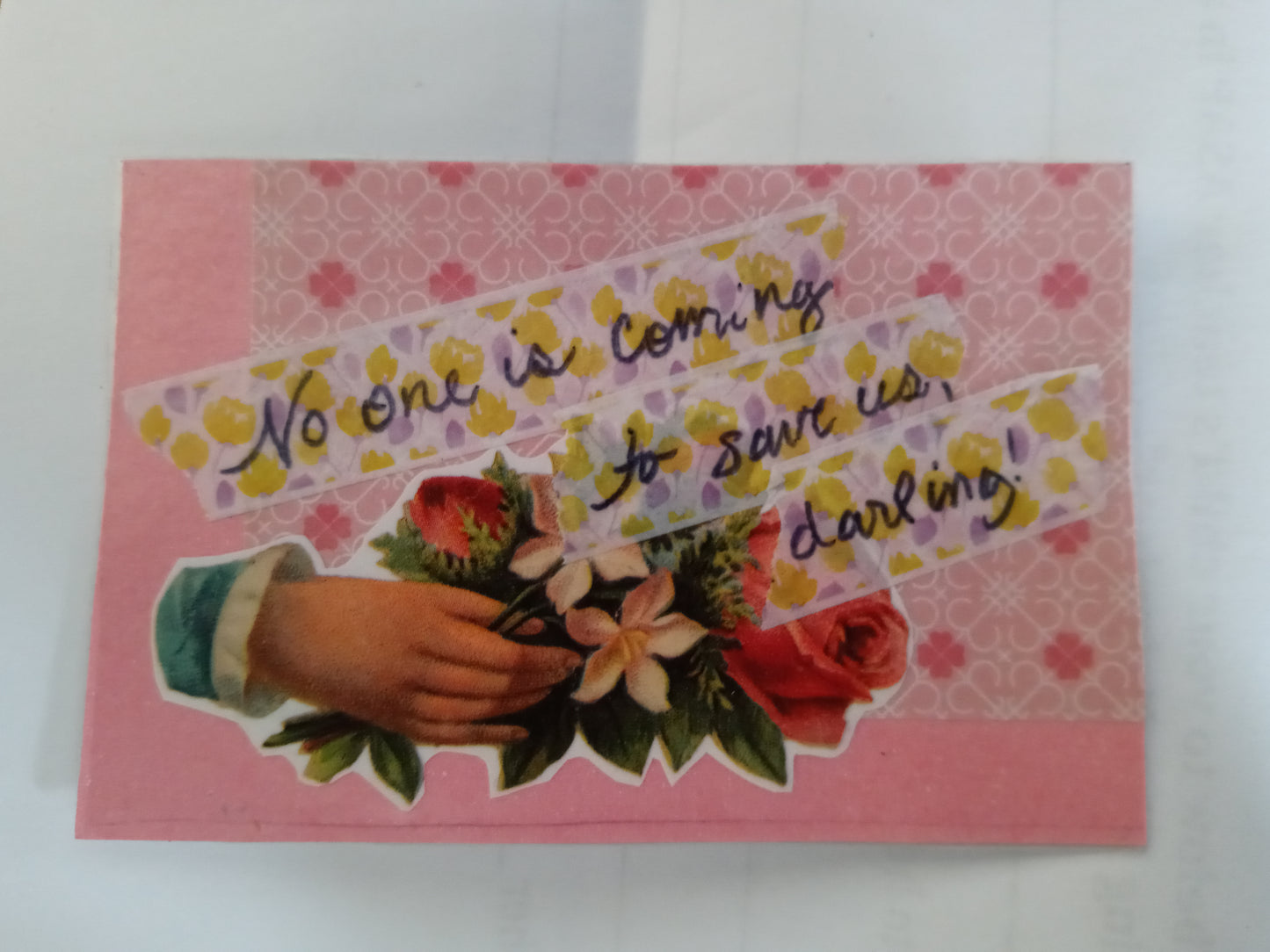 A rectangular handmade sticker on pink paper, with a variety of patterns, and a Victorian style greeting of a hand with flowers. Overlaid on purple and yellow tape is handwritten the words "No one is coming to save us, darling!"